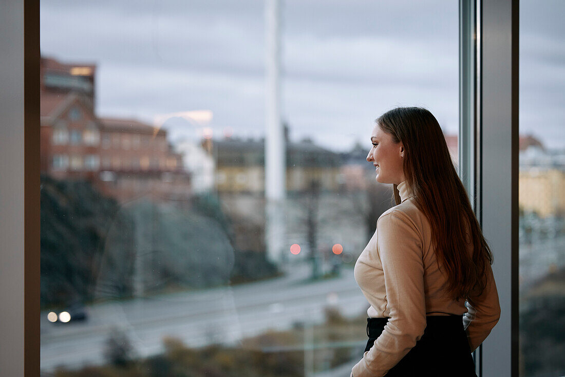 Junge Geschäftsfrau blickt durch ein Fenster