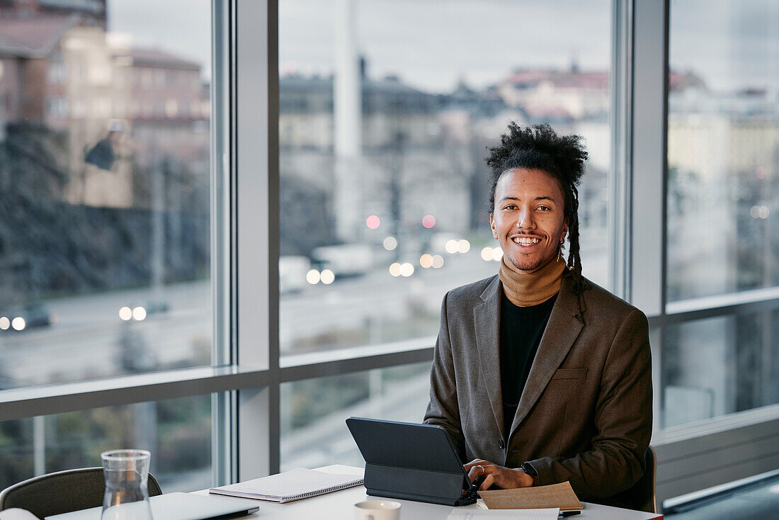 Portrait of young businessman using tablet in office