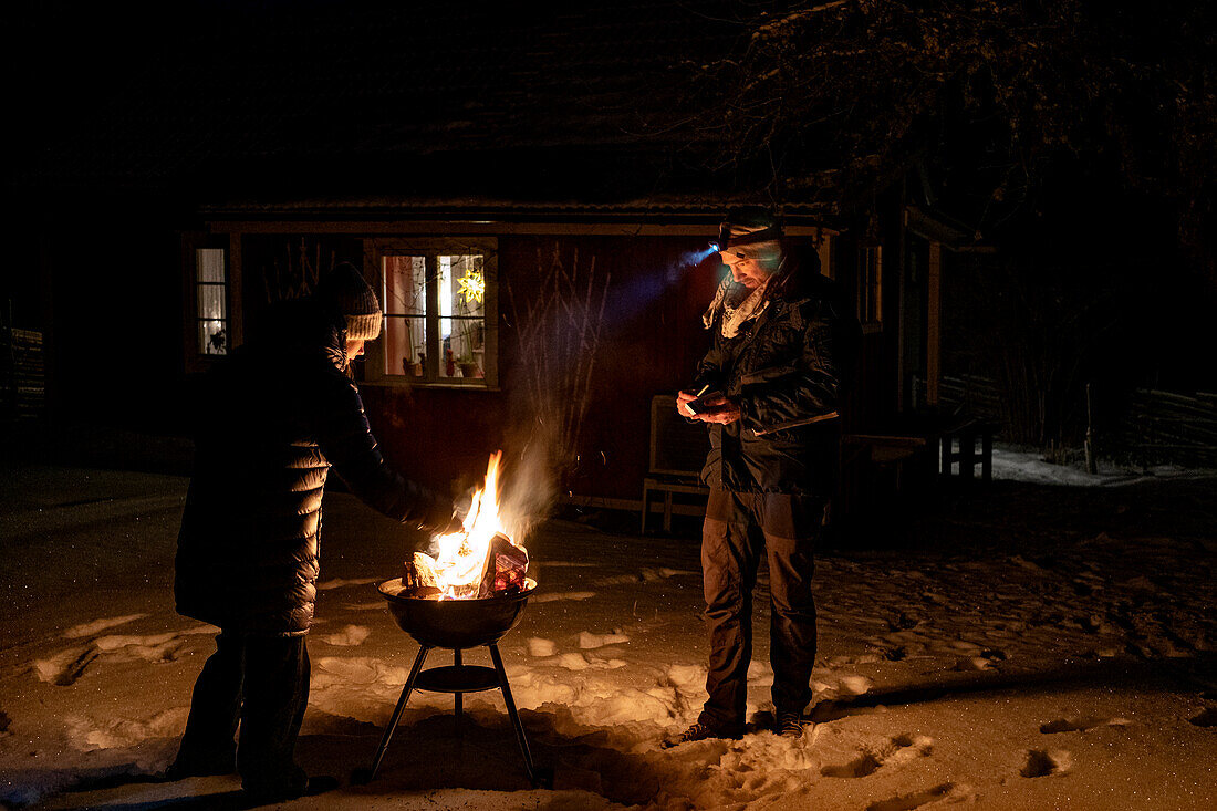 Man and woman lighting barbecue grill in winter
