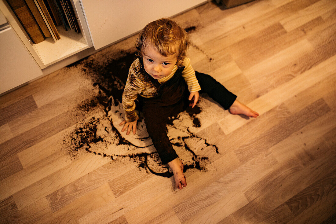 Junge sitzt auf dem Boden in verschüttetem Kaffee