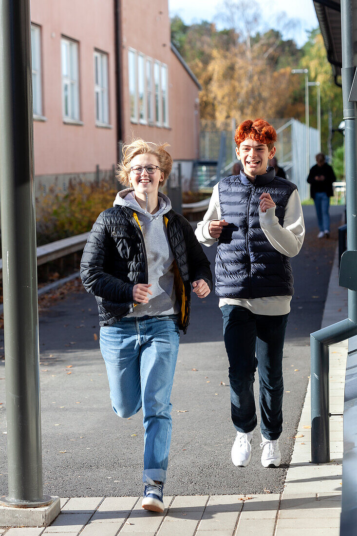 Lächelnde Teenager, die auf dem Schulhof rennen