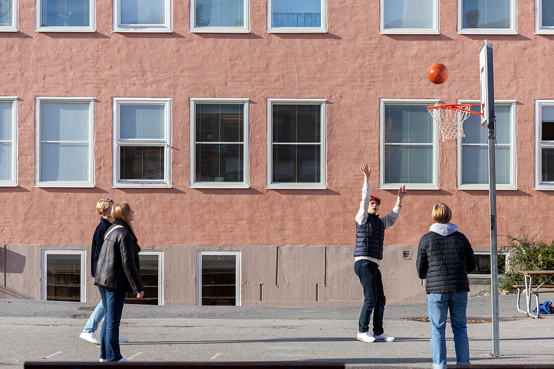 Jugendliche Jungen spielen Basketball auf dem Schulhof