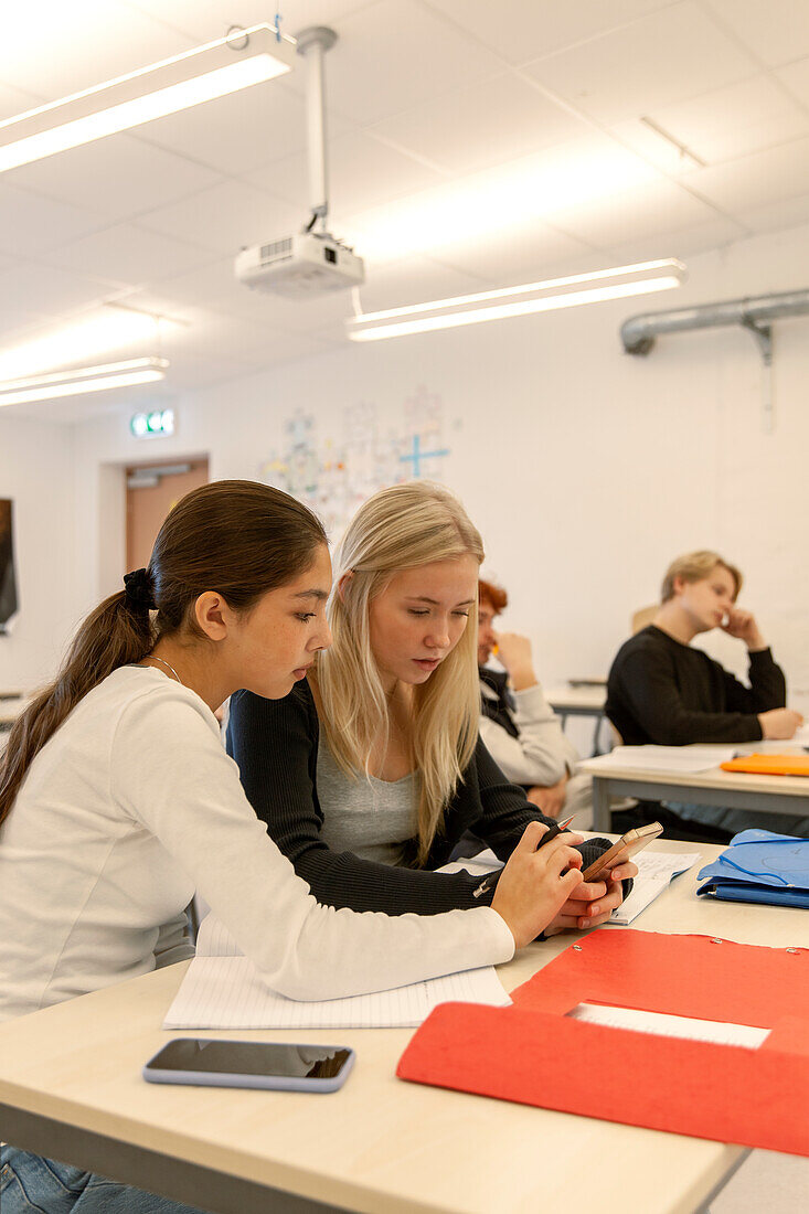 Teenager-Mädchen telefonieren im Klassenzimmer