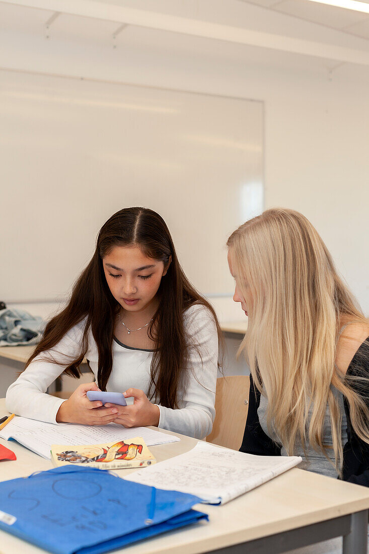 Teenager-Mädchen benutzen Telefon im Klassenzimmer