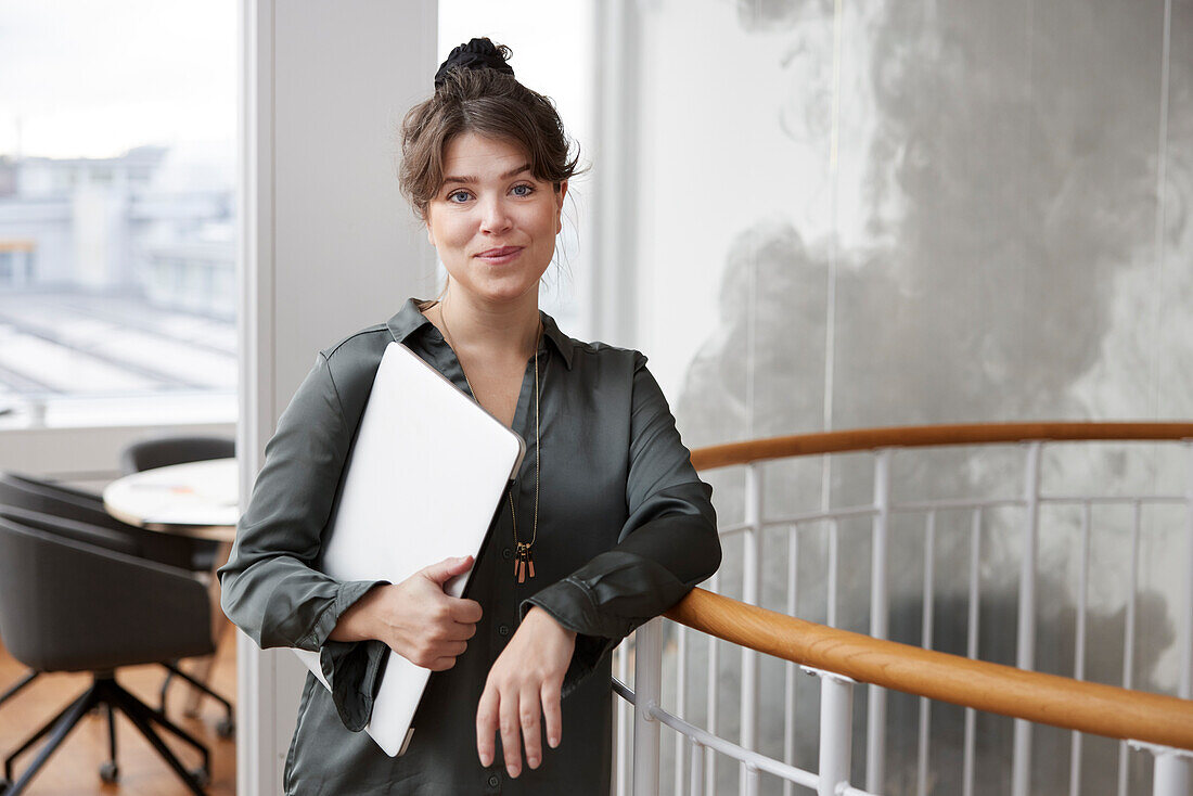 Portrait of businesswoman holding laptop in office