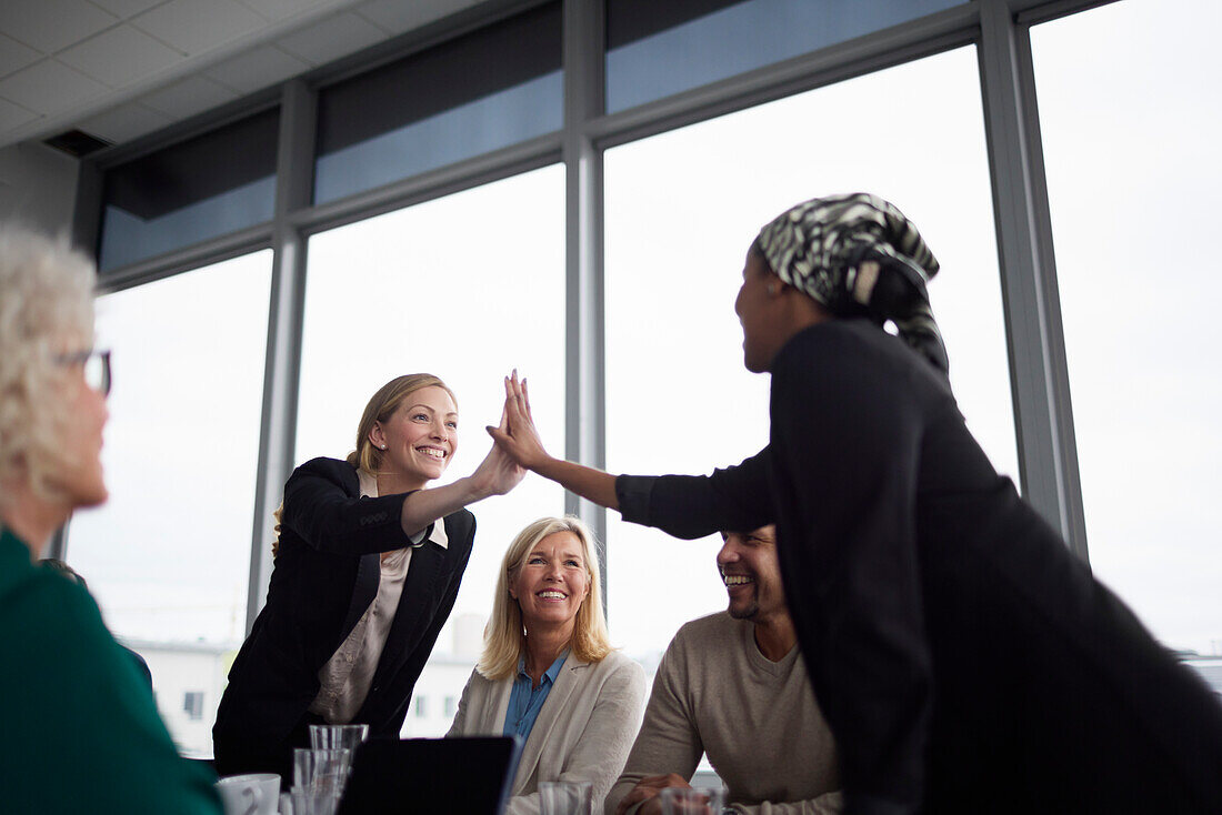 Women giving high five to each other during business meeting