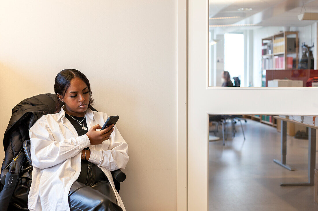 Young woman using phone in waiting room