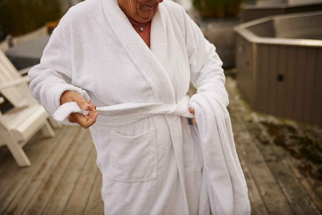 Mittelteil einer Frau beim Binden des Bademantels