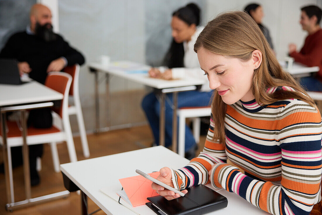 Young woman using cell phone at workshop