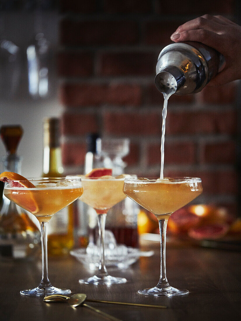 Hand gießt Getränk in Martini-Glas ein