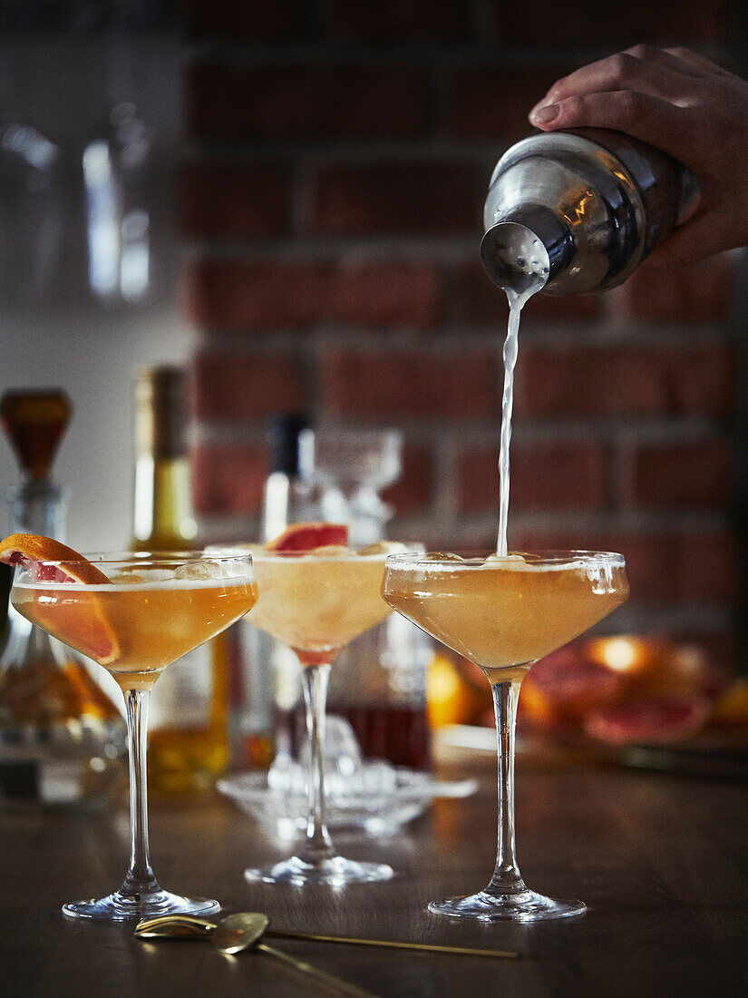 Hand pouring drink into martini glass