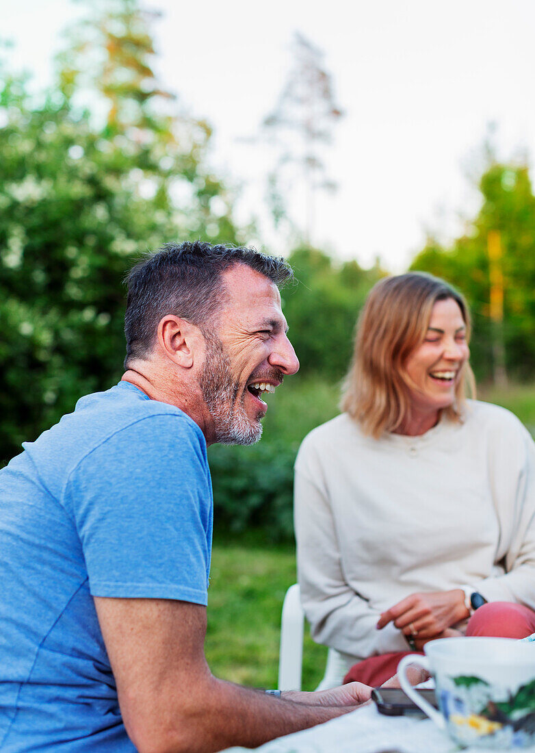 Glückliche Freunde sitzen im Garten