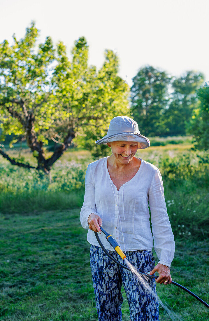 Smiling woman watering garden