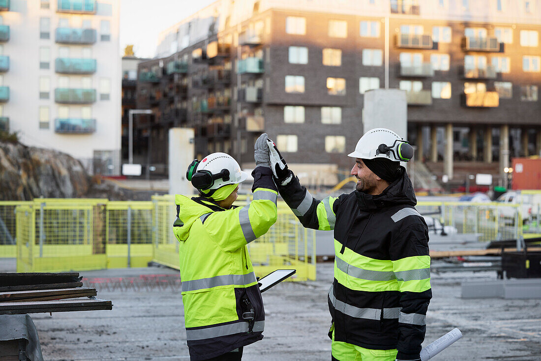 Construction engineers high-fiving at construction site