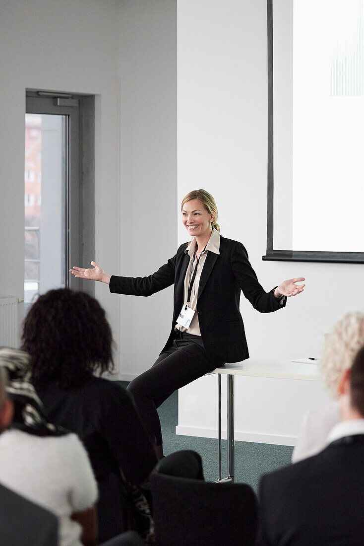 Business people sitting and listening to businesswoman