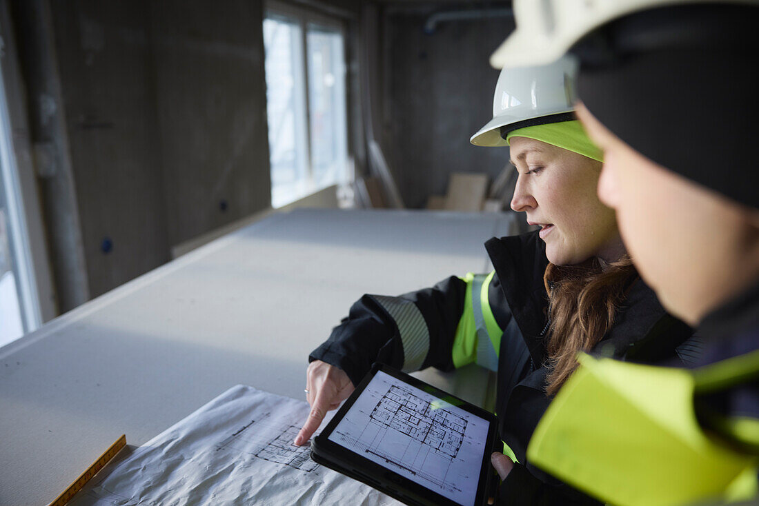 Engineers checking plans on digital tablet