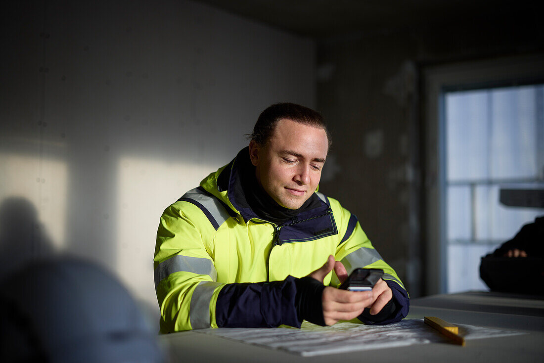 Male engineer at building site using cell phone