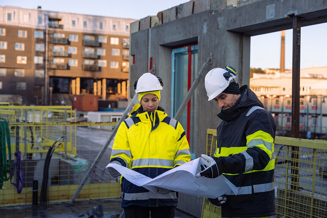 Two engineers looking at blueprints at construction site