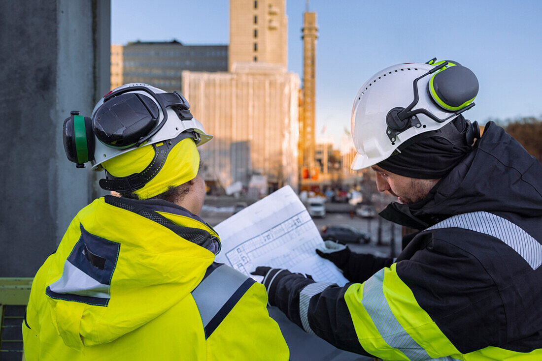 Two engineers looking at blueprints at construction site