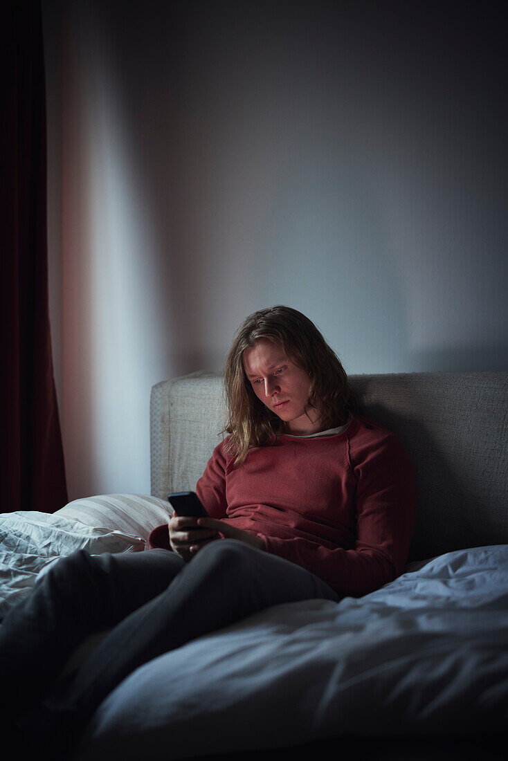 Man on bed using cell phone