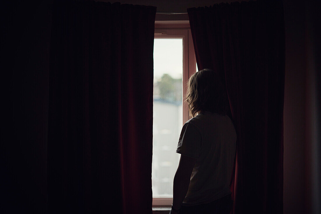 Silhouette of person looking through window