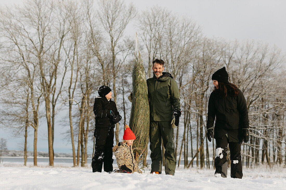 Familie mit Weihnachtsbaum im Winter