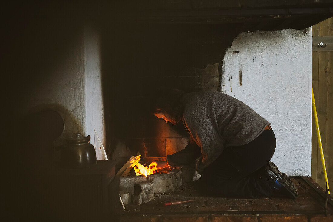 Woman preparing firewood in fireplace