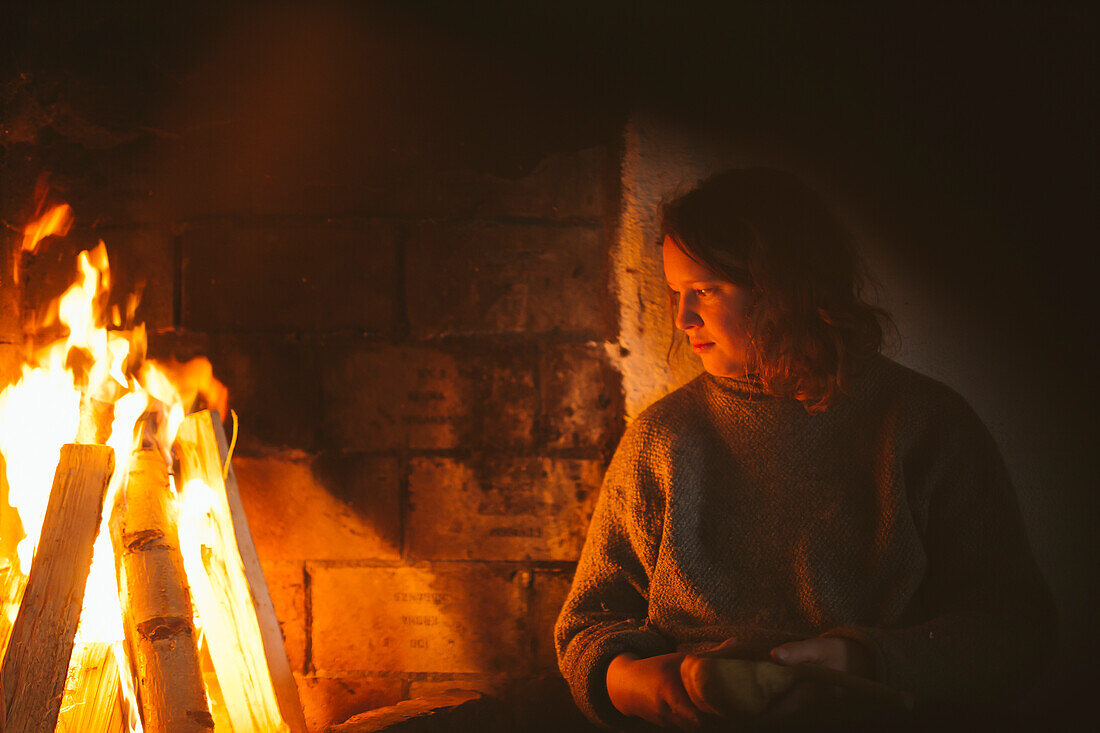 Woman sitting next to fireplace
