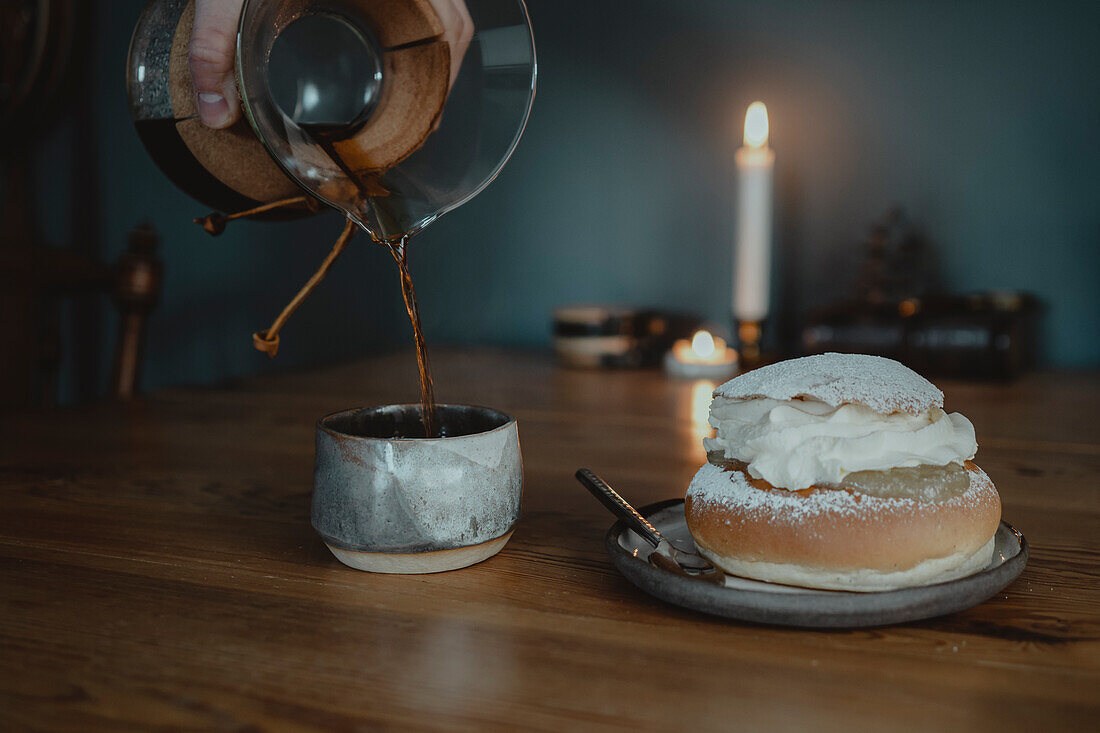 Traditional semla bun on plate and pouring coffee