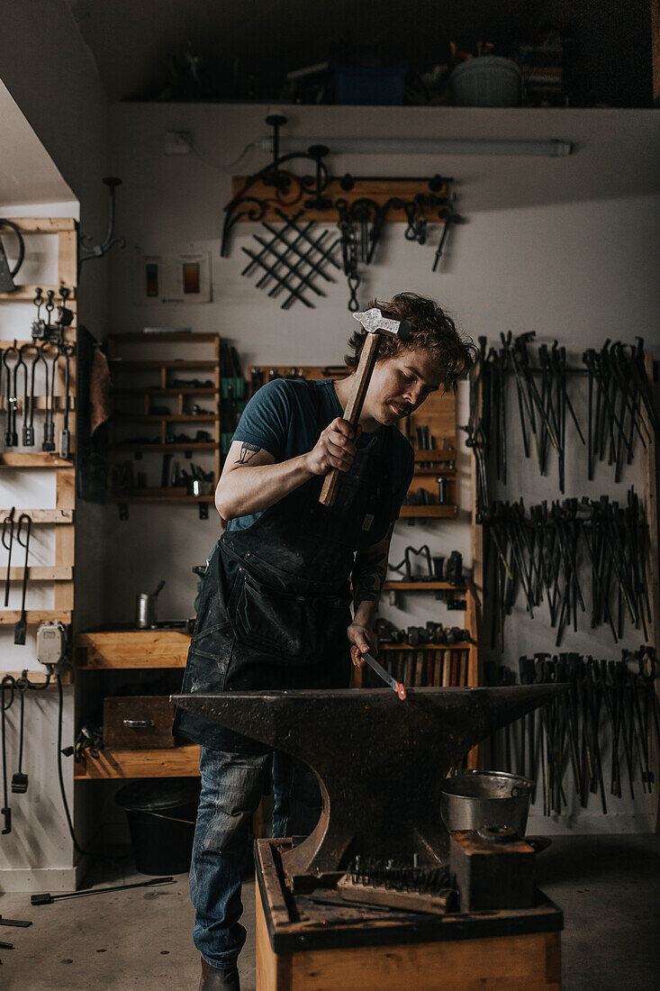 Male blacksmith hammering metal in workshop