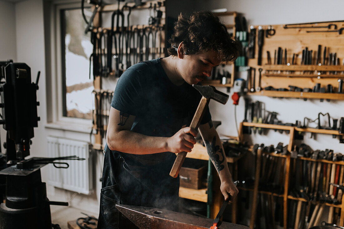 Male blacksmith hammering metal in workshop