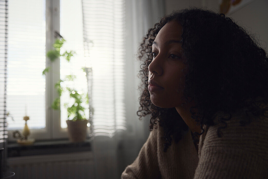 Pensive young woman sitting at home