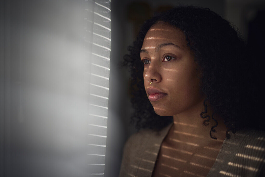 Pensive young woman looking through window