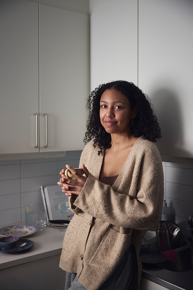 Portrait of smiling young woman standing in kitchen