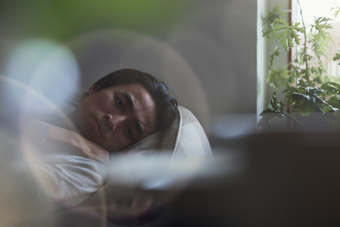 Sad man facing depression lying in bed