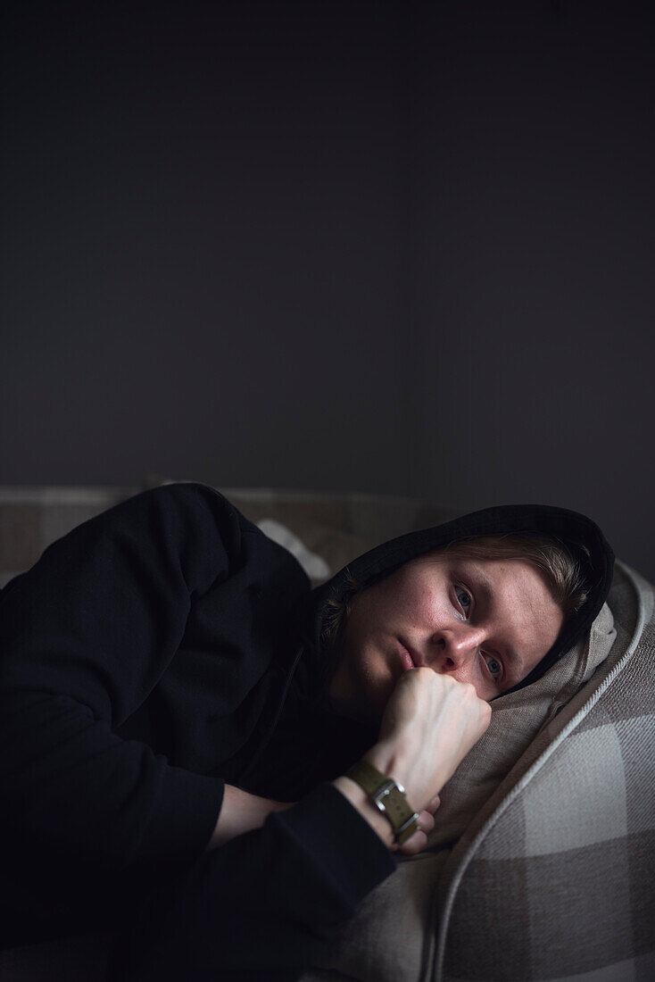 Sad man facing depression lying in bed