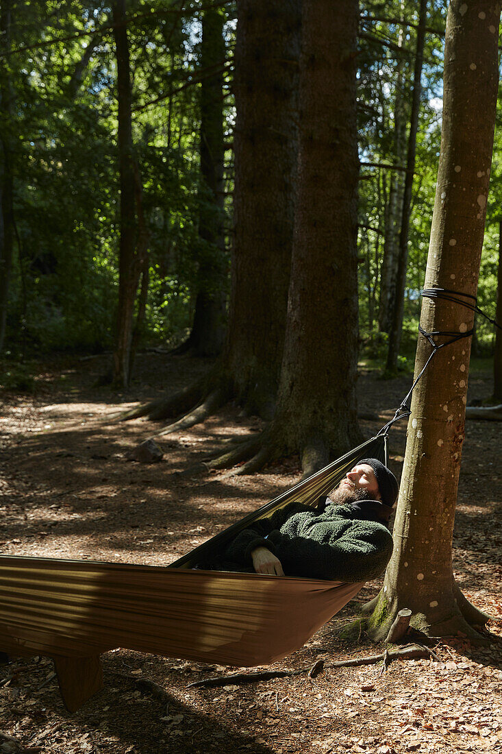 Mann schläft in Hängematte im Wald