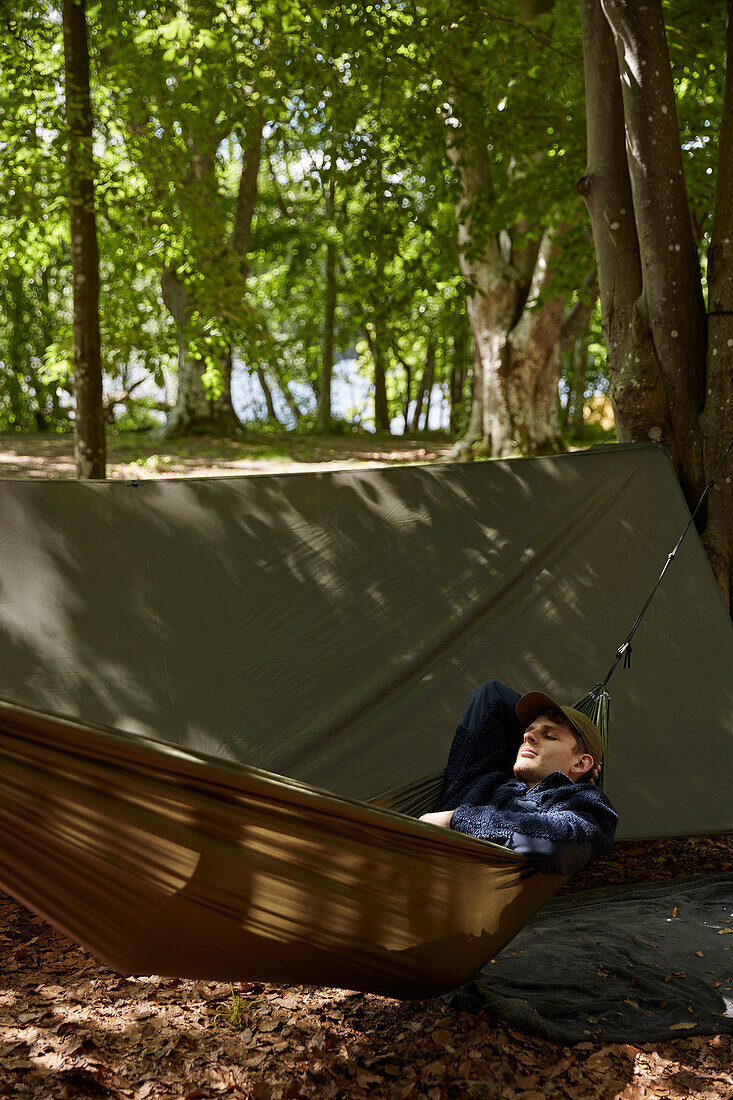 Man sleeping on hammock in forest