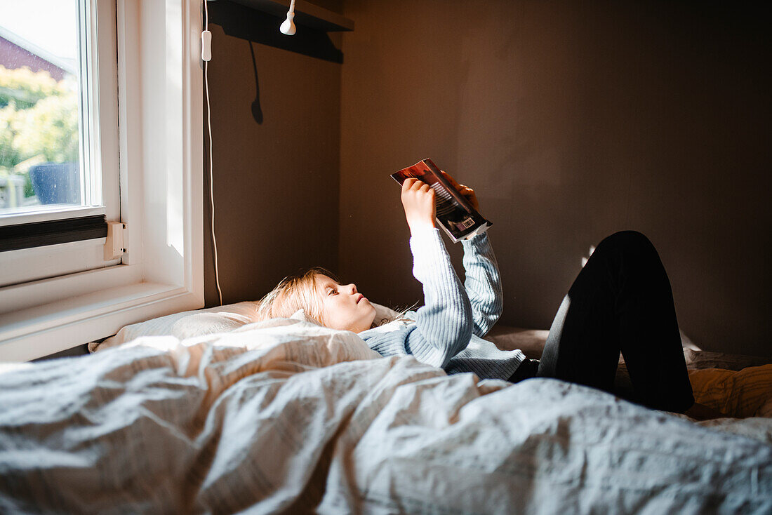 Mädchen auf dem Bett und liest ein Buch