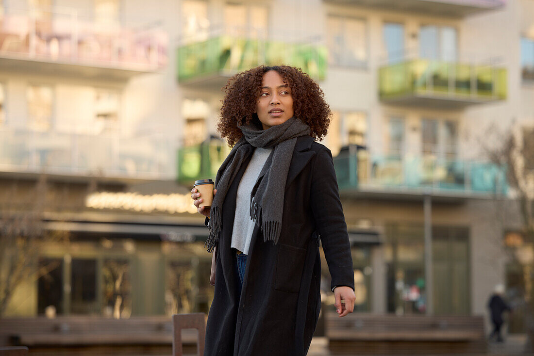 Beautiful woman with takeaway coffee walking on street