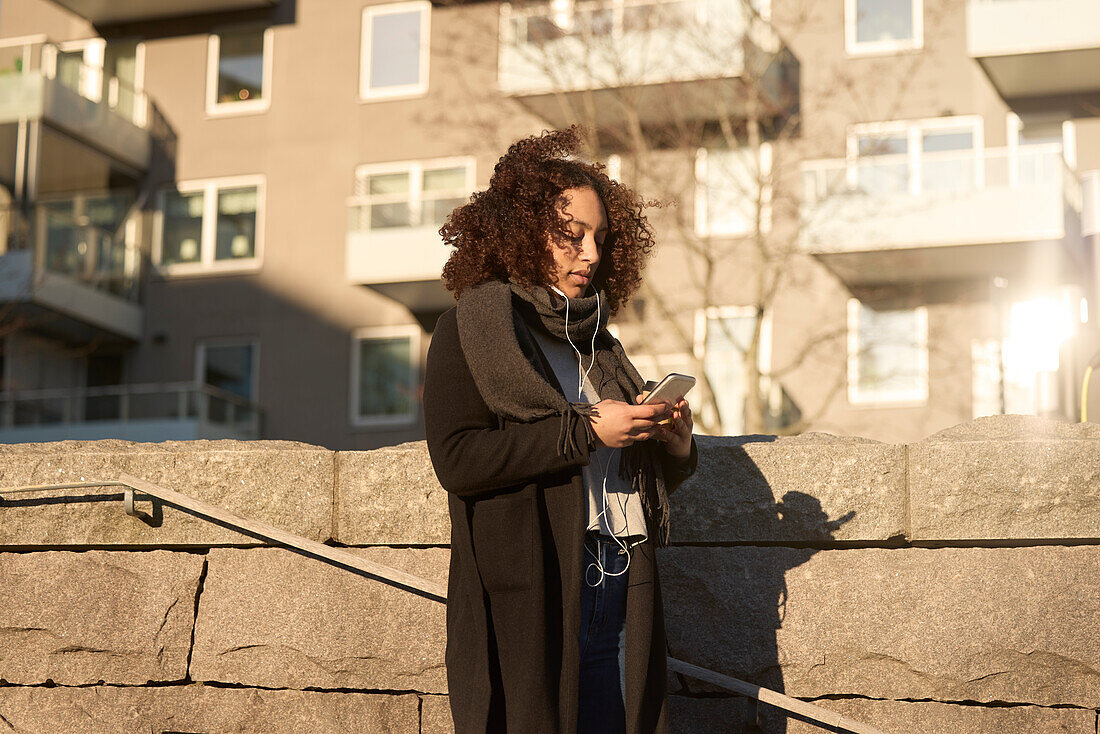 Beautiful woman with smartphone walking on street