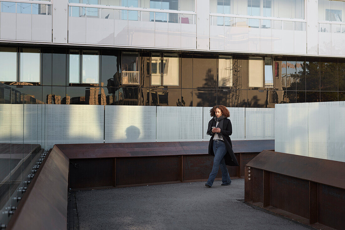 Schöne Frau mit Smartphone vor einem Bürogebäude