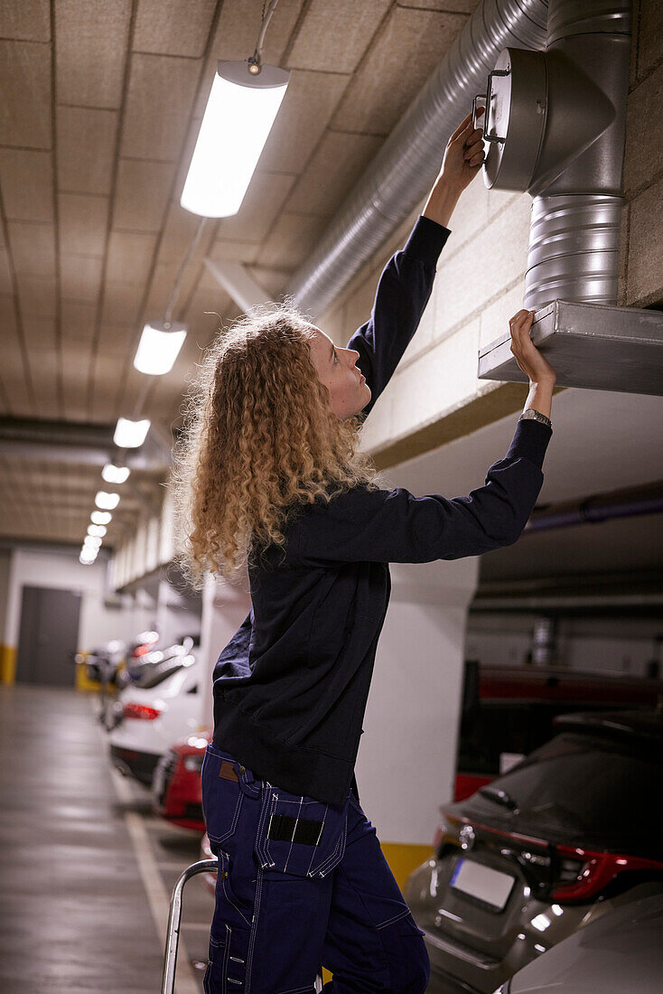 Frau prüft Luftschacht auf dem Parkplatz