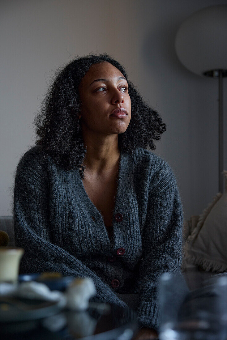 Pensive young woman sitting at home