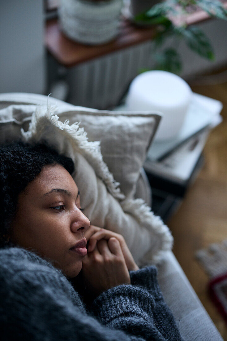 Nachdenkliche junge Frau im Bett liegend