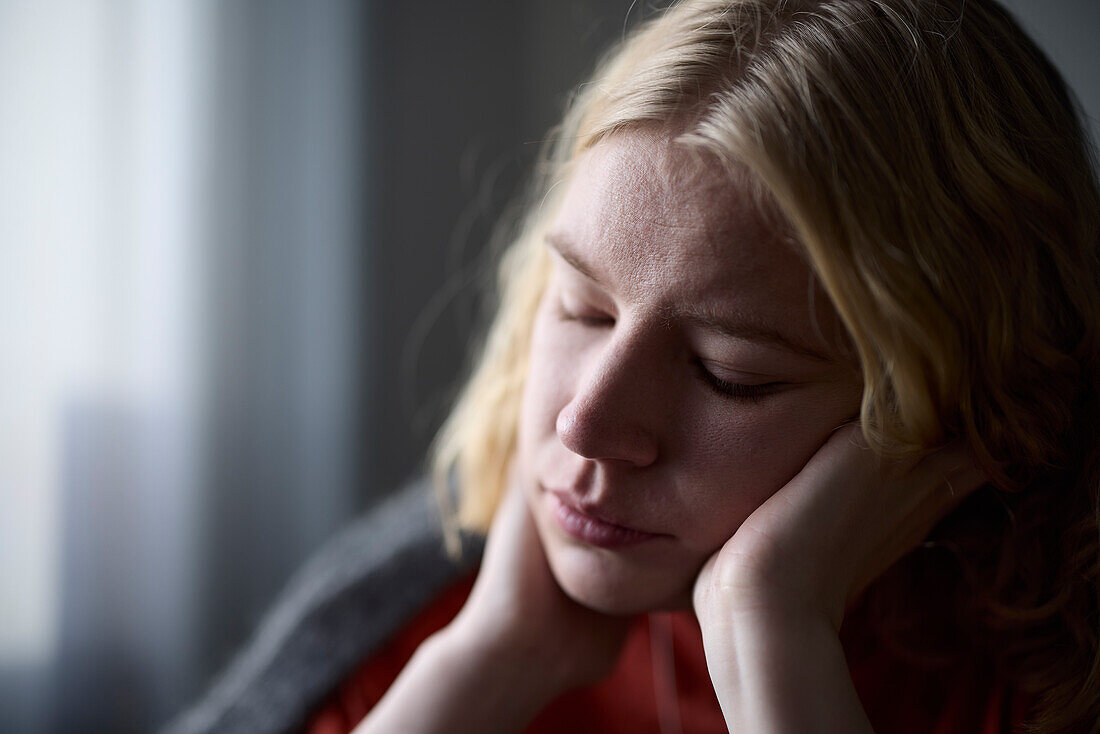 Pensive teenage girl with head in hands