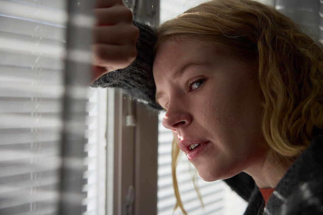 Close-up portrait of pensive teenage girl leaning against window