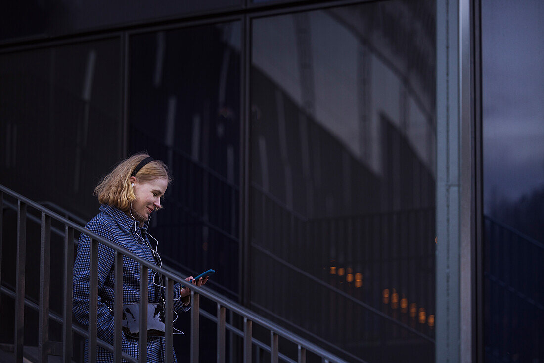 Junge Frau geht eine Treppe hinunter und benutzt ein Telefon