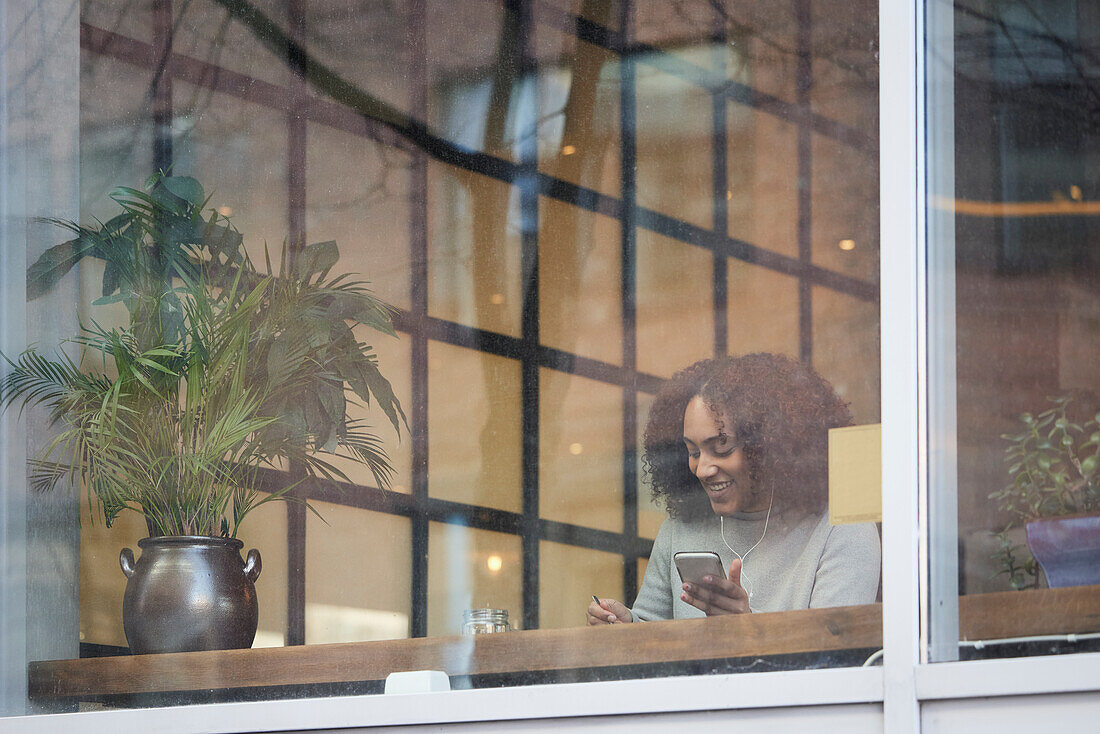 Junge Frau benutzt Mobiltelefon in einem Café