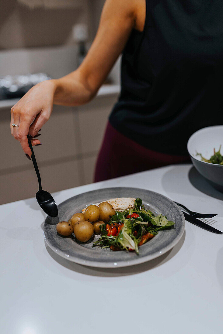 Mid section of woman putting food on plate